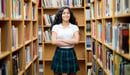A student at The Ellis School stands in the library with her arms crossed.