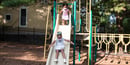 Two summer campers at The Ellis School slide down the slide on the playground.